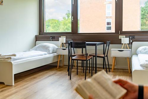 a room with two beds and a table and chairs at MC MONTI Köln Nord in Cologne
