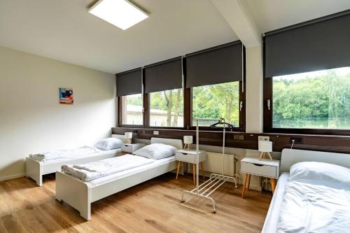 two beds in a room with two windows at MC MONTI Köln Nord in Cologne