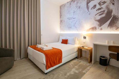 a hotel room with a bed with an orange blanket at The ICONS Lisbon Hotel in Lisbon