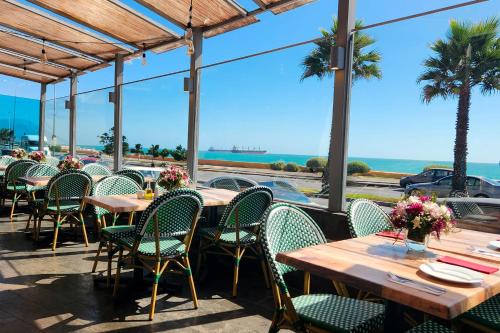 a restaurant with tables and chairs and a view of the ocean at Wyndham Garden Antofagasta Pettra in Antofagasta