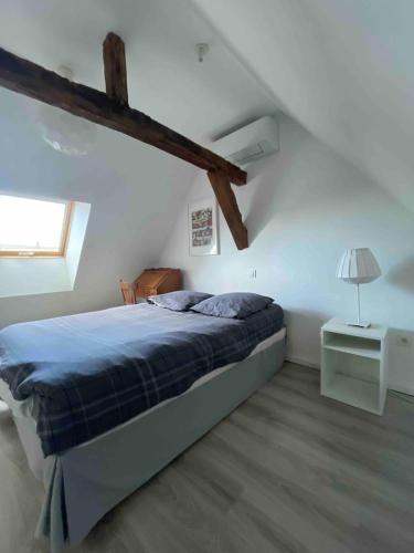 een slaapkamer met een bed en een raam op zolder bij Maison de campagne proche D'Angers in La Meignanne