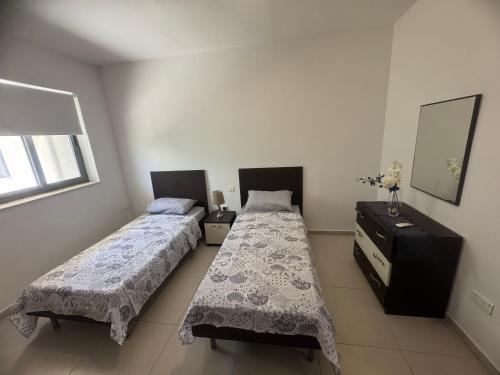 una camera con due letti e un comò di Room Cozy in San Julian 2 a San Giuliano