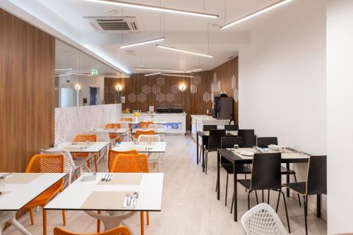 a dining room with tables and chairs and a kitchen at The ICONS Lisbon Hotel in Lisbon