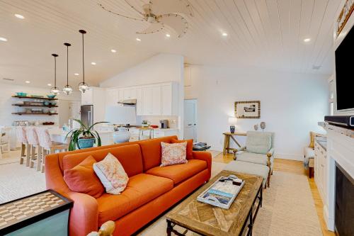 sala de estar con sofá naranja y cocina en Harbor's End, Unit A, en Boothbay Harbor