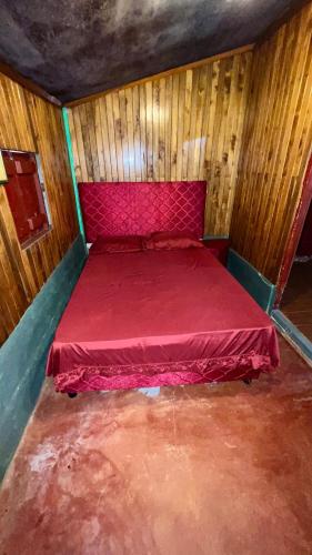 a large red bed in a room with wooden walls at Casa Rústica in Encarnación