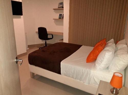 una camera da letto con un letto con cuscini arancioni e una sedia di APARTAMENTO EN ATLANTIS VISTA UNICA PISCINA JACUZZIi ad Armenia