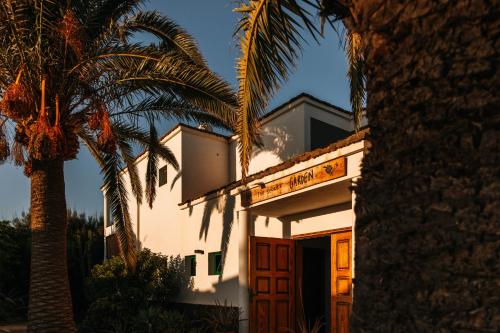 a hotel with a palm tree in front of a building at Surfescape Fuerteventura in Lajares