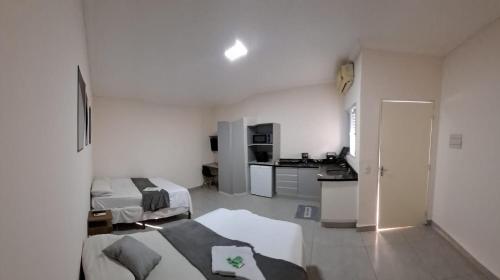 een witte kamer met 2 bedden en een keuken bij Hotel Castro Alves in Marília