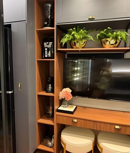 a room with a tv and some plants on shelves at Estúdio de Luxo Essenza in São Paulo