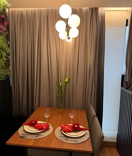 a dining room table with red napkins and a chandelier at Estúdio de Luxo Essenza in São Paulo