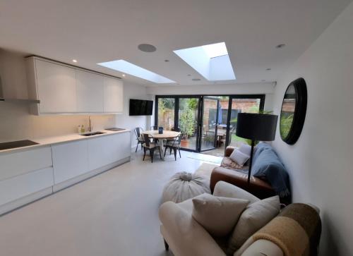 a kitchen and living room with a couch and a table at Elegant Garden Flat - Raynes Park in Raynes Park