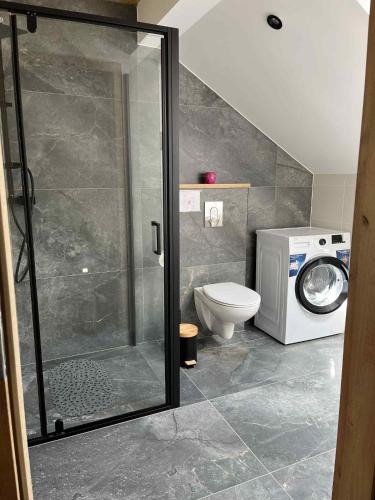 a bathroom with a shower and a washing machine at Siedlisko pod Lasem in Józefów