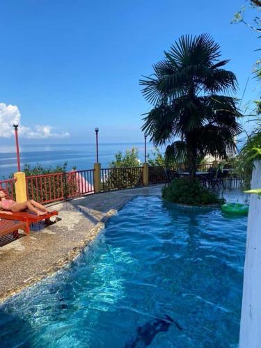a pool with blue water and a palm tree at Yellow villa in Gonio in Gonio