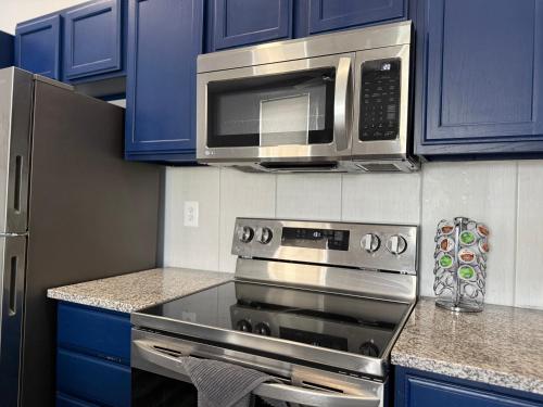 a kitchen with a stove with a microwave and blue cabinets at Modern & Quiet 1BR Apartment in Downtown - OTR - WiFi - Parking in Cincinnati