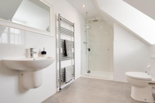 a white bathroom with a sink and a toilet at The Sandbox in Saundersfoot