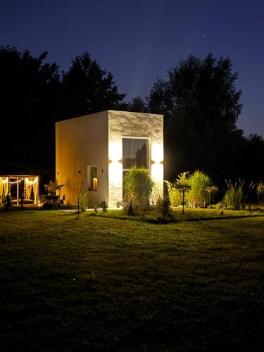 a small house with lights in a yard at night at Awangarda in Trzciel