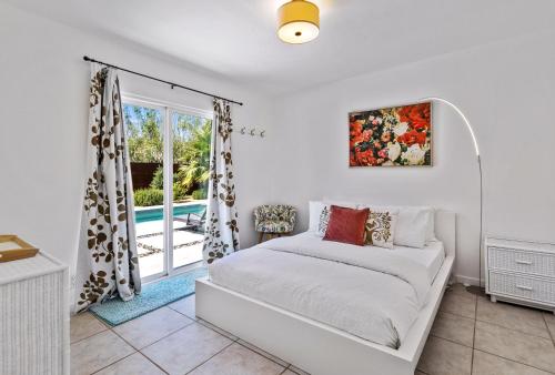 ein weißes Schlafzimmer mit einem Bett und einem Fenster in der Unterkunft Cozy Desert Bungalow in Palm Springs
