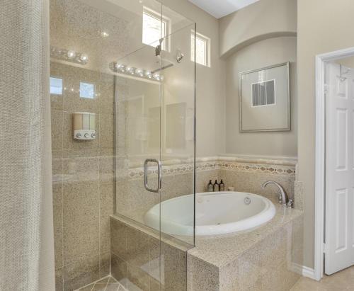 a bathroom with a tub and a glass shower at Golfing & Festival Lover's Paradise in Desert Groves Mobile Home Park