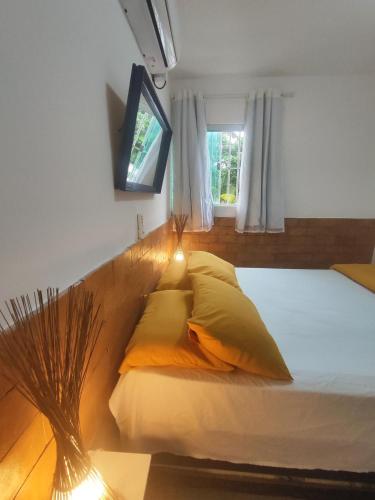 a bedroom with a bed with pillows and a window at Flat Beira-Mar Maragogi in Maragogi