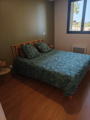 a bedroom with a bed with a blue comforter and a window at Domaine le Caprougeat in Daux