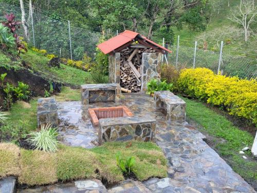 a garden with a bench and a small building at Alojamiento EL GITANO in Filandia