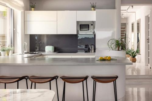 una cucina con mobili bianchi e un bancone con sgabelli di Villa King a Dubrovnik