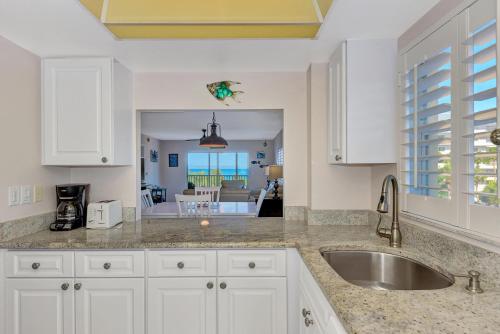 a kitchen with white cabinets and a sink at Playing Hooky in Siesta Key