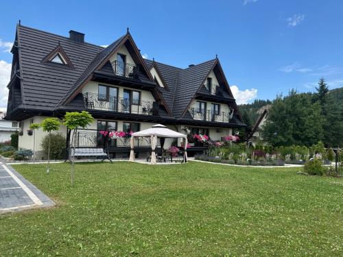 a large black house with a lawn in front of it at Suchowianka Ski&Relax in Białka Tatrzańska