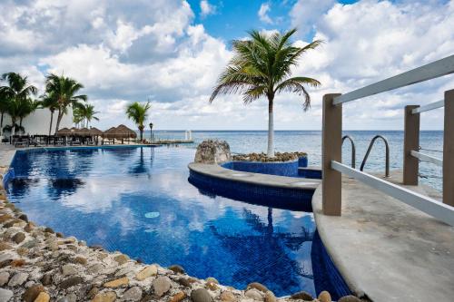 una piscina vicino all'oceano con palme di Oceanfront Luxury -4-King Suites Dive Pick Ups-Walk to Dining & Shops a Cozumel