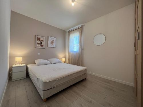 a white bedroom with a bed and a window at Le temps de vivre in Mormoiron