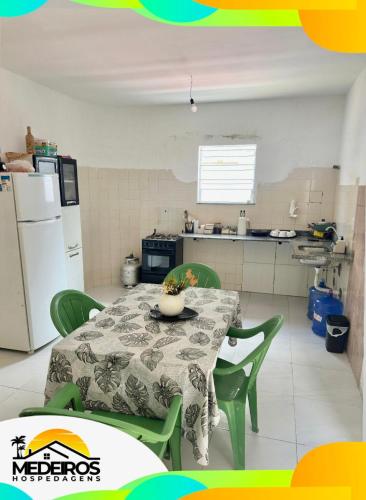 a kitchen with a table and green chairs and a refrigerator at Casa próxima à litorânea! in São Luís