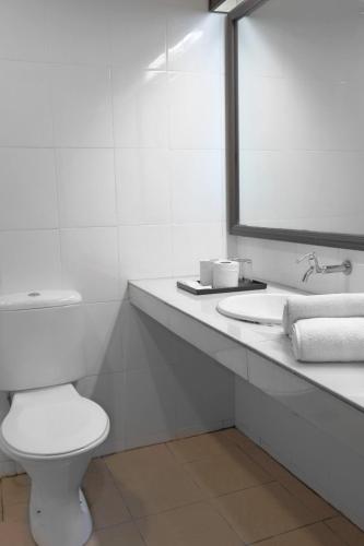a white bathroom with a toilet and a mirror at Garden Inn, Penang in George Town