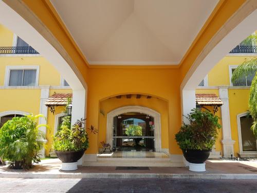 an entrance to a yellow building with potted plants at Hotel Hacienda Real in Ciudad del Carmen