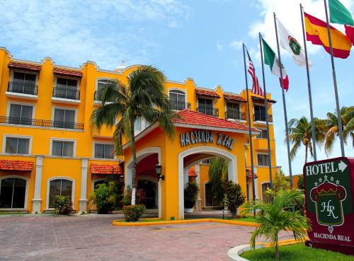 a yellow hotel with flags in front of it at Hotel Hacienda Real in Ciudad del Carmen