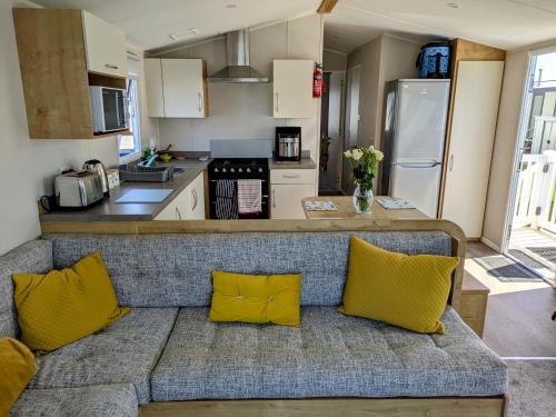 a couch with two yellow pillows in a kitchen at Seascape Caravan in Kinmel Bay