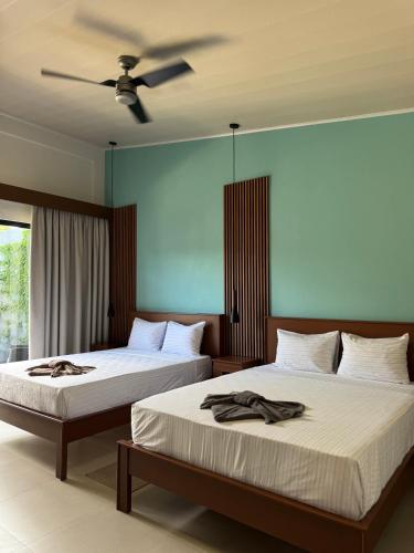 a bedroom with two beds and a ceiling fan at Jardín de Martín - Hotel Boutique in Puerto Jiménez