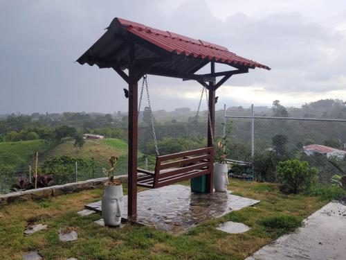 a wooden bench with a canopy on top of a hill at Alojamiento EL GITANO in Filandia