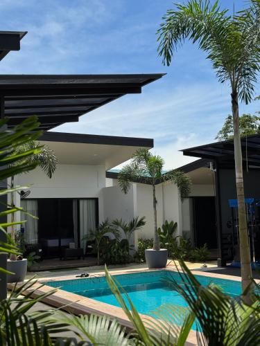 a swimming pool in front of a house with palm trees at Jardín de Martín - Hotel Boutique in Puerto Jiménez