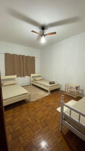a room with two beds and a ceiling fan at Aconchego! in Barretos