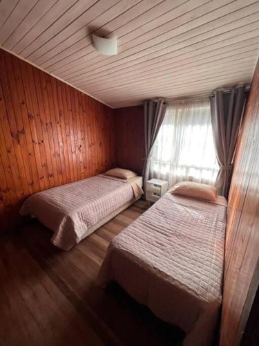 a bedroom with two beds and a window at Casa Luma in Puerto Montt
