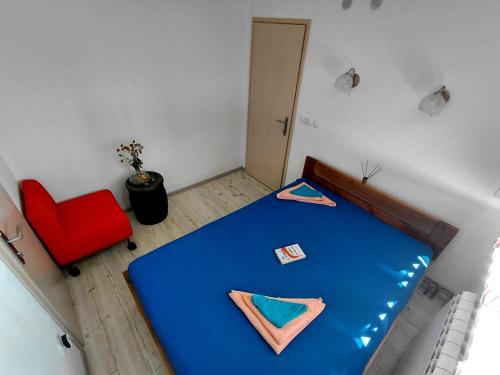 a bedroom with a blue bed and a red chair at Kremna Sunset in Kremna