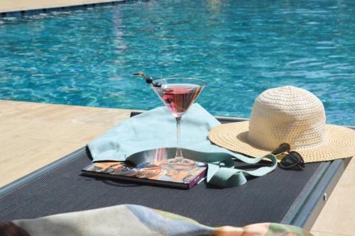 a drink and a hat on a table next to a pool at Ballı Butik hotel in Kayakoy