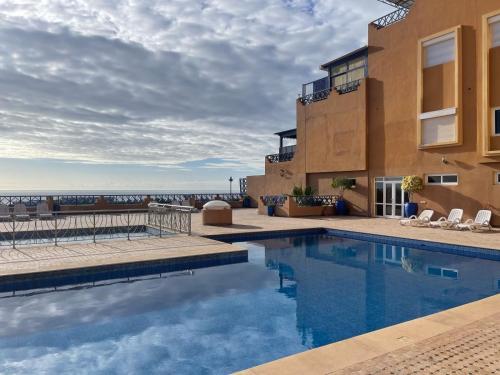 einem Pool vor einem Gebäude mit Meerblick in der Unterkunft Tamraght apartment with Pool access in Tamraght Ouzdar