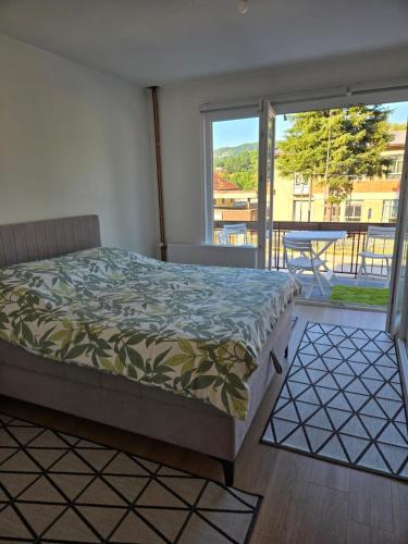 a bedroom with a bed and a view of a balcony at Urban Home Visoko in Visoko