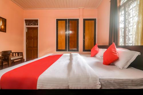 a bedroom with a large bed with red and white pillows at Collection O Trinayan Associates in Dibrugarh