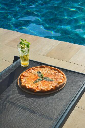 a pizza sitting on a table next to a swimming pool at Ballı Butik hotel in Kayakoy