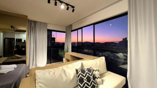 a living room with a couch and a large window at CURTA! |165| Lindo Studio | Próx Centro de Eventos in Camboriú