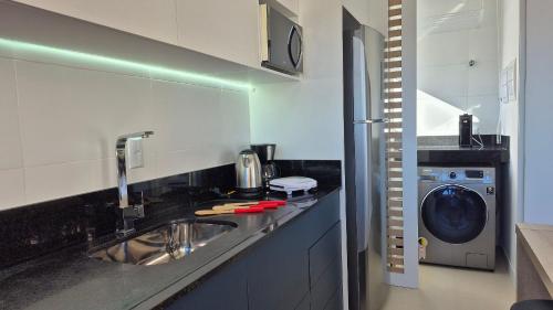 a kitchen with a sink and a washing machine at CURTA! |165| Lindo Studio | Próx Centro de Eventos in Camboriú