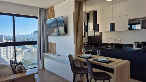 a kitchen with a table and chairs in a room at CURTA! |165| Lindo Studio | Próx Centro de Eventos in Camboriú
