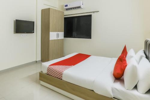 a bedroom with a bed with red pillows and a tv at Hotel O Zion Inn in Vapi